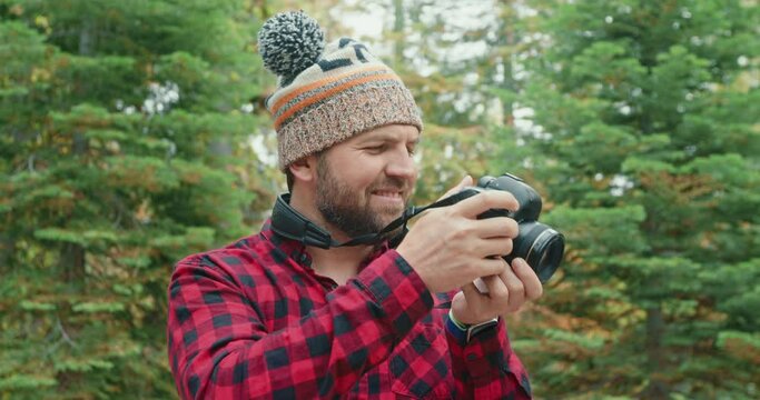 Forest hiker photographer in woods. 30s smiling man shooting green forest. Male portrait footage concept. Modern traveler guy taking pictures of scenic nature view and cinematic early fall landscape