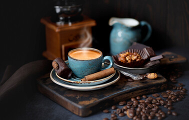 A Cup of hot coffee on a rustic Board with coffee beans and cinnamon sticks