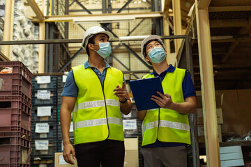 Group of young factory warehouse workers wearing a protective face mask while working in logistic...