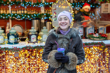 Obraz na płótnie Canvas Beautiful young woman with coffee cup in the city. Beautiful woman with coffee on the street in winter clothes. Woman Having Hot Drink Outdoors On Winter Market. toned