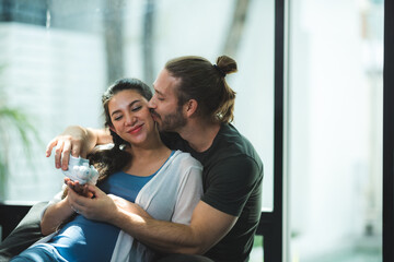 Beautiful pregnant woman and her handsome husband are talking and kissing while spending time together in bed