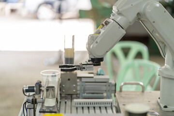 Man is holding a teach pendant to control a robot arm that is integrated into a smart factory production line. automation line which is equipped with sensors and robot arm. Selective Focus.
