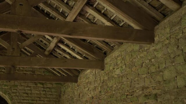 Wooden roof beams in old stone building wide shot