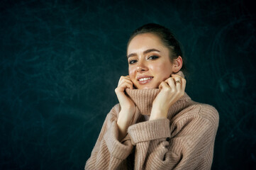 portrait of a young woman in a warm knitted sweater on a dark background .
