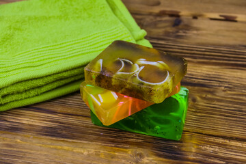 Set of handmade soap bars and towel on wooden background