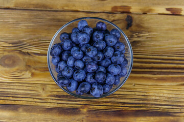 Fresh blueberry in glass bowl on a wooden table. Top view