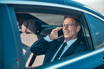 Cheerful businessman talking on smartphone during transfer from airport