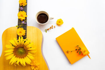 notebook planner ,hot cocoa, guitar and yellow flowers cosmos, sunflowers  of lifestyle arrangement flat lay style on background white 