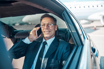 Happy businessman making call after landing by plane