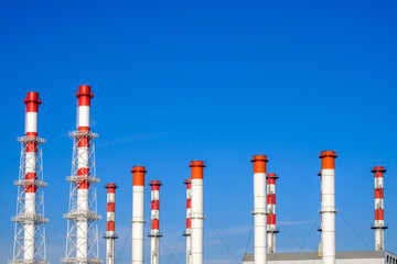A lot of white and red industrial pipes against the background of a cloudless blue sky on a sunny...