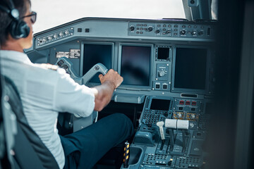 Male professional in uniform driving passenger airplane