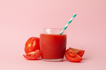 Glass with fresh tomato juice on pink background