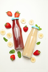Bottles with strawberry and banana juices on white background