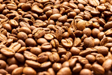 Roasted arabica coffee beans scattered in a heap on the table.