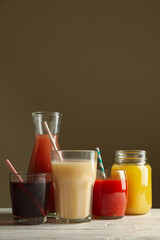 Glasses and jars with different juices on white wooden table
