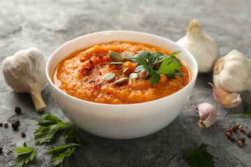 Composition with bowl of pumpkin soup on gray background, close up