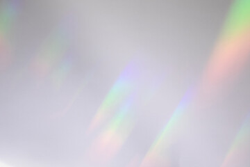 Blurred rainbow light refraction texture overlay effect for photo and mockups. Organic drop diagonal holographic flare on a white wall. Shadows for natural light effects