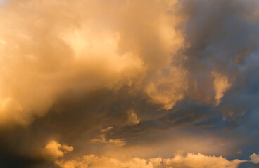 Section of sky with cumulus and rain clouds at sunset