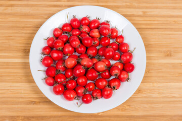 Harvested fruits of hawthorn on dish on the wooden surface