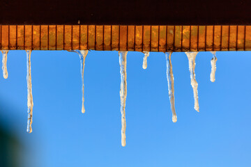 Icicles in winter against a blue sky.