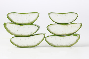 Aloe vera cut into pieces, stacked on a white background.