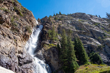 Burkhan bulak waterfall, the highest waterfall in Kazakhstan. Waterfall with strong stream is flowing among rocky mountains. Outdoor landscape. Tourism in Kazakhstan concept. Summer vacation concept.