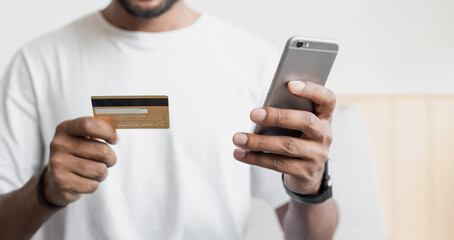 Closeup of man hands holding credit card and using smartphone at home, businessman shopping online, e-commerce, internet banking, spending money, working from home concept