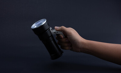 hand holding a flashlight on dark background.