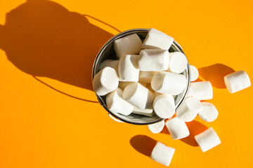 White marshmallows in a white metal bucket on a yellow background copy space, an ingredient for...