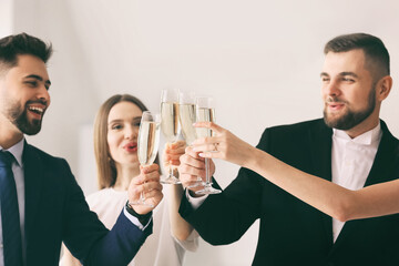Young people clinking glasses of tasty champagne at party in office