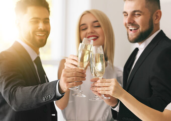 Young people clinking glasses of tasty champagne at party in office