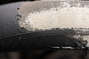 Torn black fabric on a leather office armchair background texture. worn upholstery chair