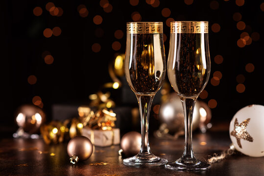 Christmas champagne, gas bubbles, confetti and blurry lights on a dark background.