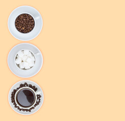 Three cups on saucers with sugar cubes, coffee and coffee beans on a beige background. Free space for text. The view from the top.