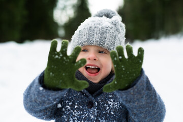 Front view of small child standing in snow, holiday in winter nature.
