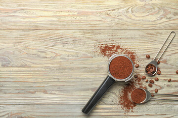 Portafilter with coffee powder and beans on wooden background