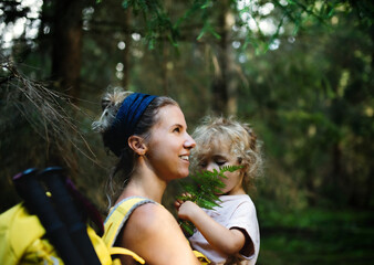 Side view of mother with small daughter outdoors in summer nature, resting.