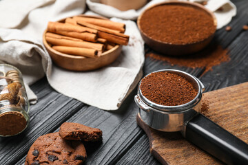 Portafilter with coffee powder, spices and cookies on dark wooden background
