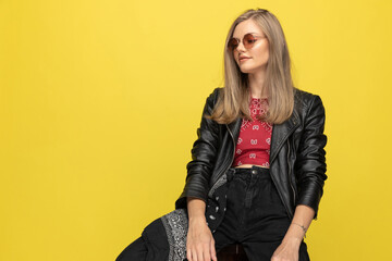 Positive fashion model wearing sunglasses and smiling, looking away