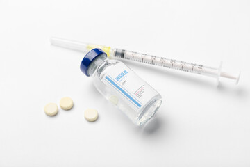 Bottle of insulin with syringe and pills on white background. Diabetes concept