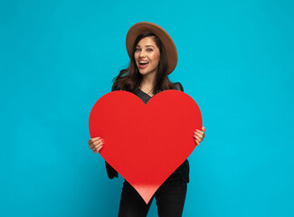 Positive casual woman holding heart shape and laughing