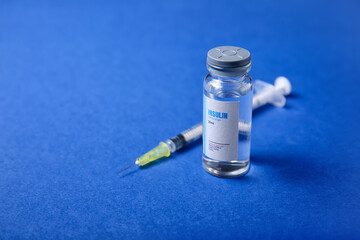 Bottle of insulin with syringe on color background. Diabetes concept