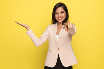 confident businesswoman in pink suit pointing finger and presenting