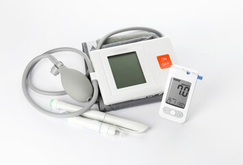Glucometer with sphygmomanometer, syringe and lancet pen on white background. Diabetes concept