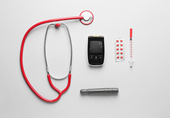 Glucometer, pills, stethoscope, syringe and lancet pen on white background. Diabetes concept