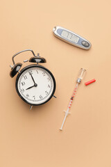 Glucometer with alarm clock, syringe and bottle of insulin on color background. Diabetes concept