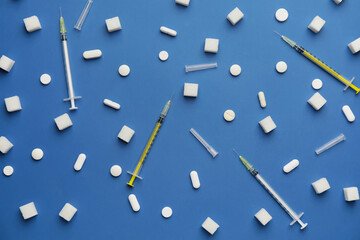 Sugar cubes with pills and syringes on color background. Diabetes concept
