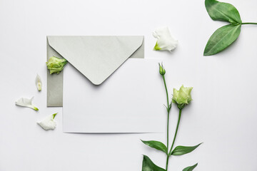 Composition with blank card, envelope and flowers on white background