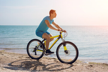 Fototapeta premium Young man bicycling along a beach