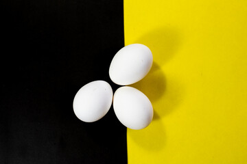 three eggs on black and yellow contrasting color background
